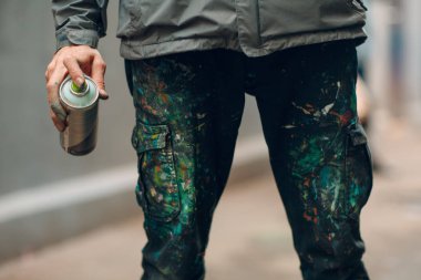 Grafiti sanatçısı elinde boya spreyi ile giysiler içinde.
