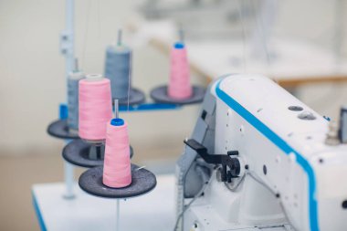 Genç, güzel terzi fabrikadaki dikiş makinesine dikiş dikiyor.