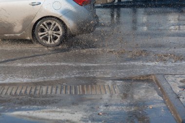 Araç, eriyen kardan oluşan su birikintilerinin içinden geçiyor. Tekerleklerin altından püskürt.