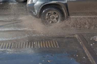 Araç, eriyen kardan oluşan su birikintilerinin içinden geçiyor. Tekerleklerin altından püskürt.