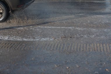 Araç, eriyen kardan oluşan su birikintilerinin içinden geçiyor. Tekerleklerin altından püskürt.