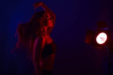 İç çamaşırlı genç bir kadın kırmızı arka ışıkta poz veriyor.