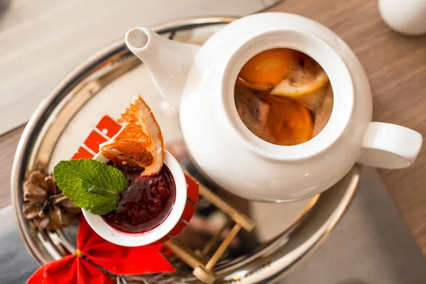 Moroccan tea with orange and lemon in a teapot with raspberry jam and spices