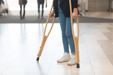 Koltuk değnekli kotlu kız. Yüzü yok.