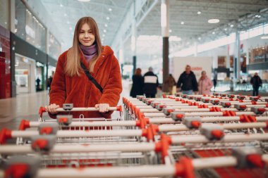 Süpermarkette market arabalarının yanındaki genç kadın.
