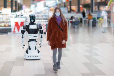 Genç bayan alışverişçi yürüyor ve dükkanda robot danışmanı var.