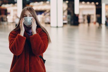 İçerideki tıbbi maskeli genç kadın.