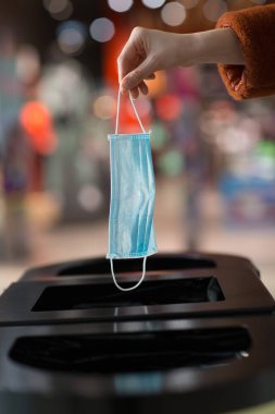 Kadın çöpe tıbbi maske atıyor.