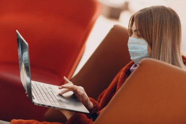 Maskeli ve dizüstü bilgisayarlı genç bir kadın.