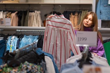 Genç bir kadın mağazadan kıyafet seçiyor.