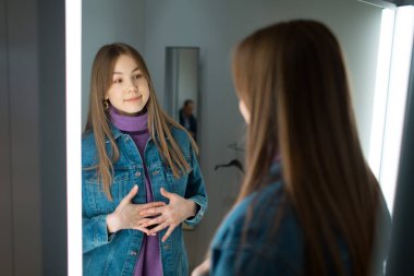 Genç bir kadın soyunma odasında aynasını dükkanda dener.