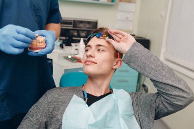 Diş hekimliği. Diş hekimi hastaya implantlar gösteriyor. Diş Kliniği.