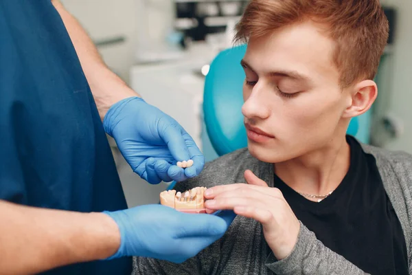 Diş hekimliği. Diş hekimi hastaya implantlar gösteriyor. Diş Kliniği.