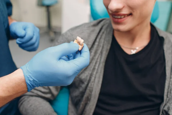 歯医者は歯科医院の患者にインプラントを示します — ストック写真
