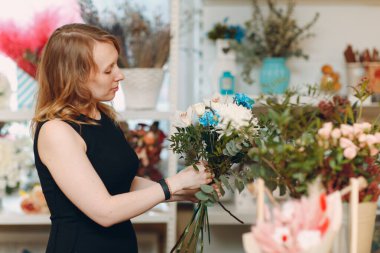 Çiçekçi butikte buket yapıyor.