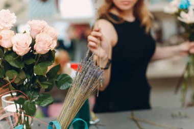 Çiçekçi butikte buket yapıyor.