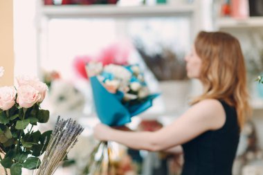 Çiçekçi butikte buket yapıyor.