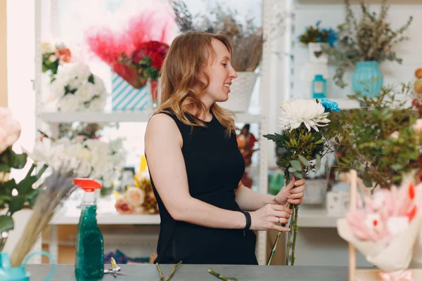 Florist makes a bouquet in a flower boutique