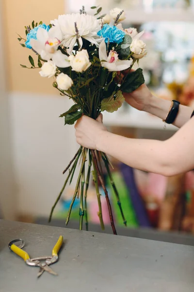 Florist makes a bouquet in a flower boutique