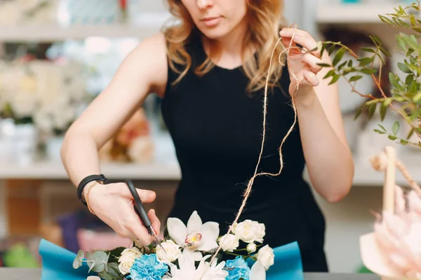 Florist makes a bouquet in a flower boutique