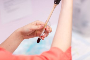 Laboratuvardaki laboratuvar asistanı elinde kan ve plazmayla test tüpü tutuyor ve analiz yapıyor..