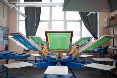 İpek ekran yazdırma. Serigrafi. Renkli boyalar ve kumaş. Atlıkarınca makinesi.