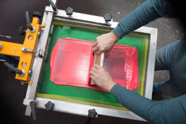 İpek ekran yazdırma. Serigrafi. Renkli boyalar ve kumaş. Plastisol boya ve cam sileceği..