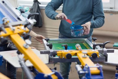 İpek ekran yazdırma. Serigrafi. Renkli boyalar ve kumaş. Atlıkarınca makinesi.