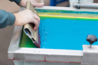 İpek ekran yazdırma. Serigrafi. Renkli boyalar ve kumaş. Plastisol boya ve cam sileceği..