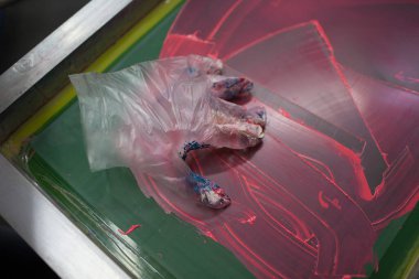 İpek ekran yazdırma. Serigrafi. Renkli boyalar ve kumaş. Eldiven.