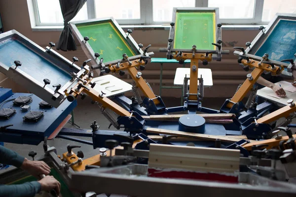 İpek ekran yazdırma. Serigrafi. Renkli boyalar ve kumaş. Atlıkarınca makinesi.