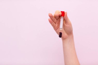 Laboratuvardaki laboratuvar asistanı elinde kan ve plazmayla test tüpü tutuyor ve analiz yapıyor..