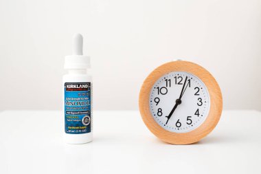 Beyaz masa arkaplanındaki Minoxidil ve Alarm Saati
