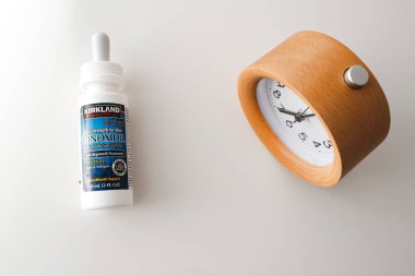 Beyaz masa arkaplanındaki Minoxidil ve Alarm Saati
