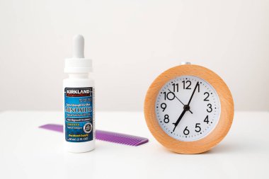 Beyaz masa arkaplanındaki Minoxidil ve Alarm Saati