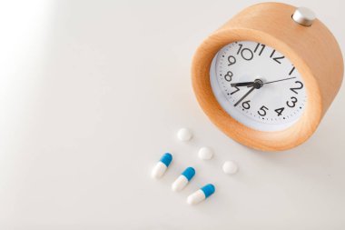 Alarm saati ve beyaz masa arkasında beyaz mavi haplar
