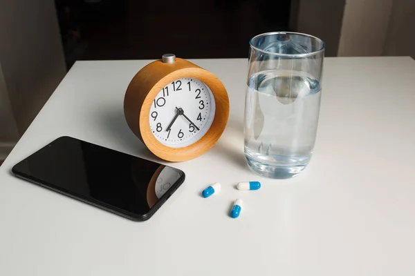 Reloj Despertador Vaso Agua Teléfono Móvil Píldoras Blancas Sobre Fondo — Foto de Stock