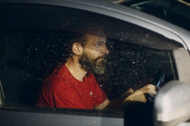 Şoför yağmurlu gecelerde direksiyonda oturur.