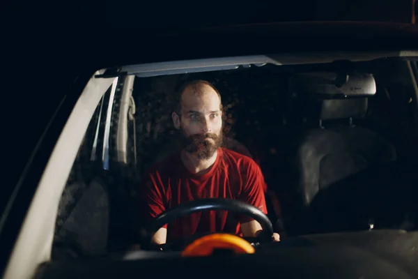 Man driver sits at steering wheel of car at night