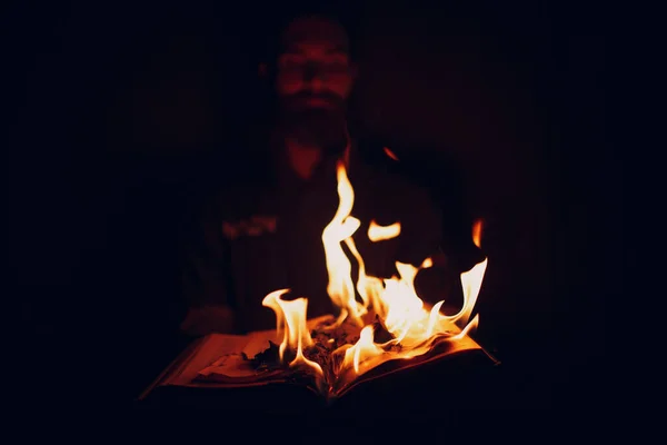 Man holds burning book in his hands.