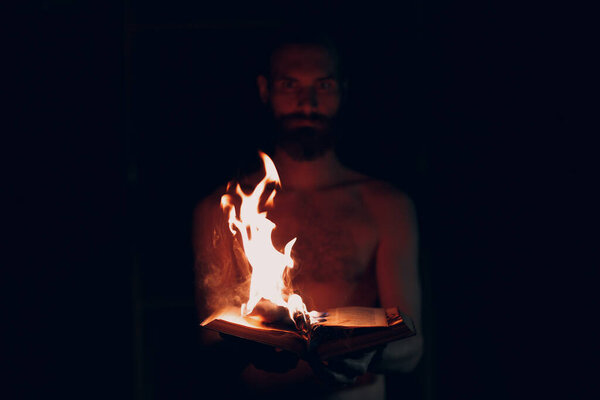 Man holds burning book in his hands.