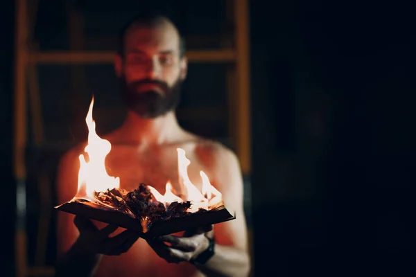 Man holds burning book in his hands.