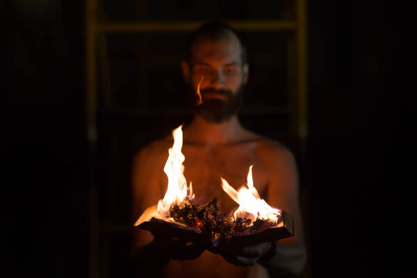 Man holds burning book in his hands.