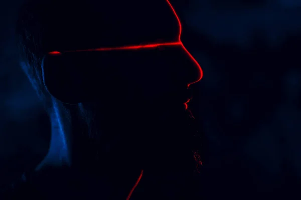Man in dark with face illuminated by red laser on contour