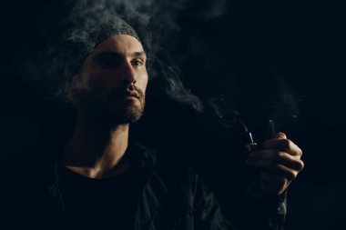Siyah arka planda pipo içen bir adam