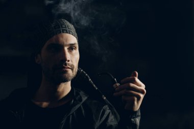 Siyah arka planda pipo içen bir adam