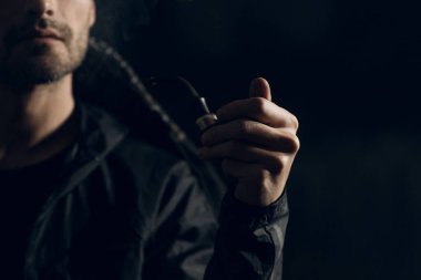 Siyah arka planda pipo içen bir adam