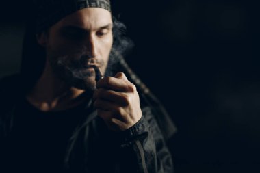 Siyah arka planda pipo içen bir adam