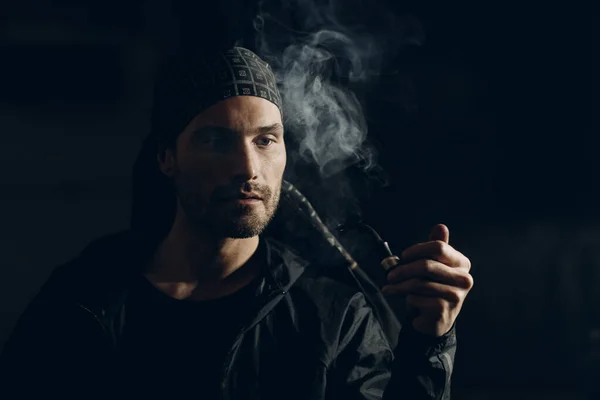 Man smoking a pipe on dark background