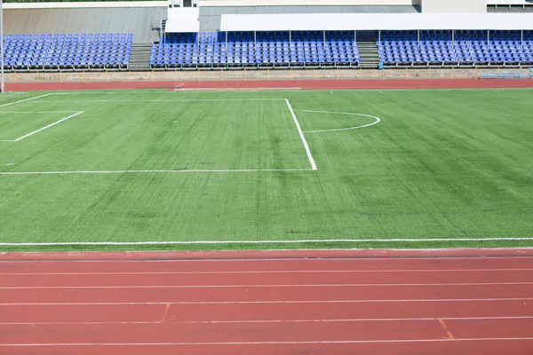 Running track and field with green grass for football at stadium